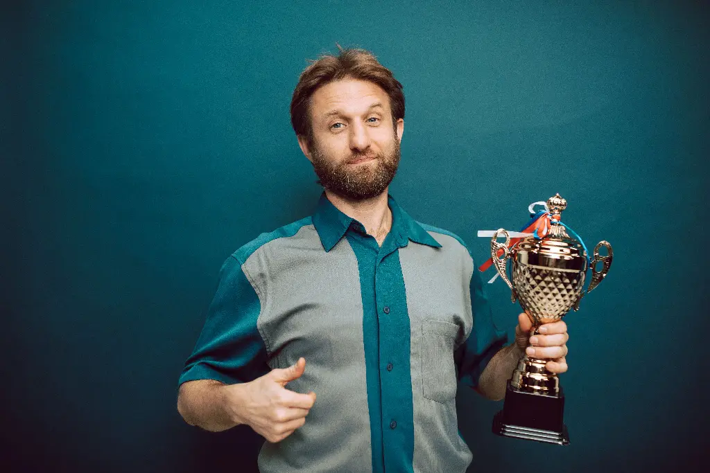 Man holding a shiny trophy award with a smile. Image depicting award.