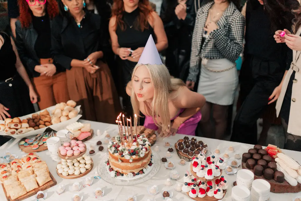 Girl blowing candles on birthday cake, celebrating with friends. Image depicting celebrate.