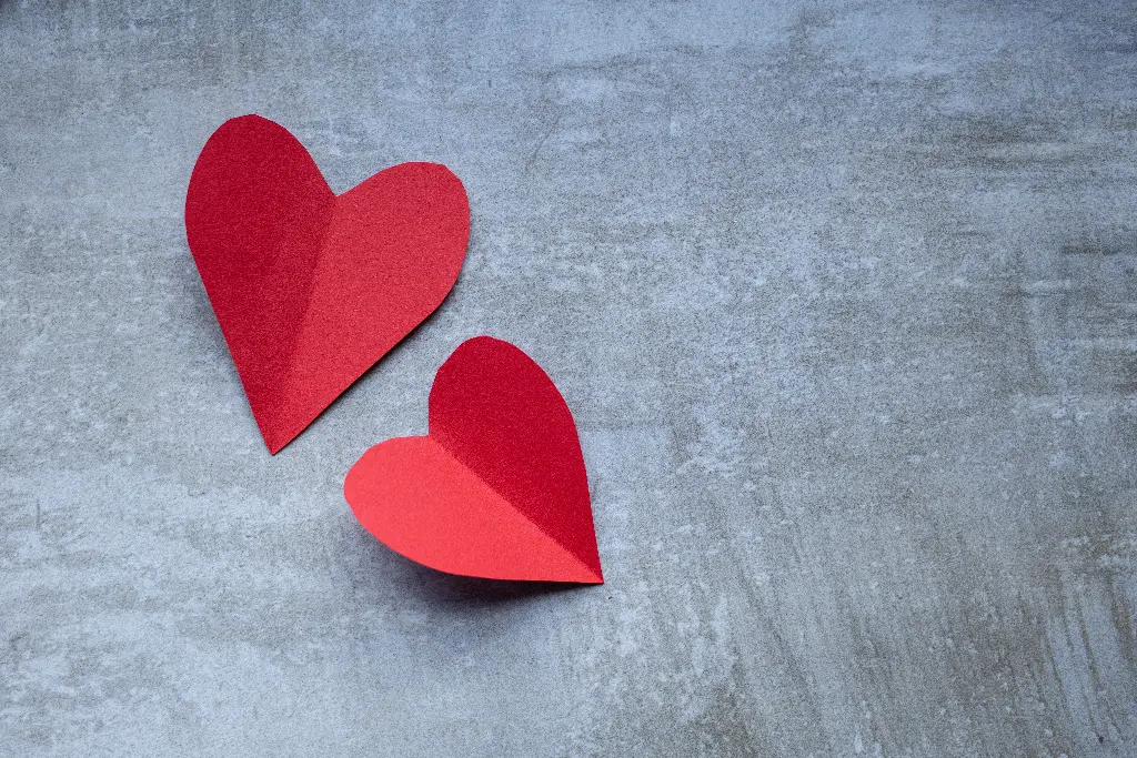 Two red paper hearts on gray background Image depicting heart.