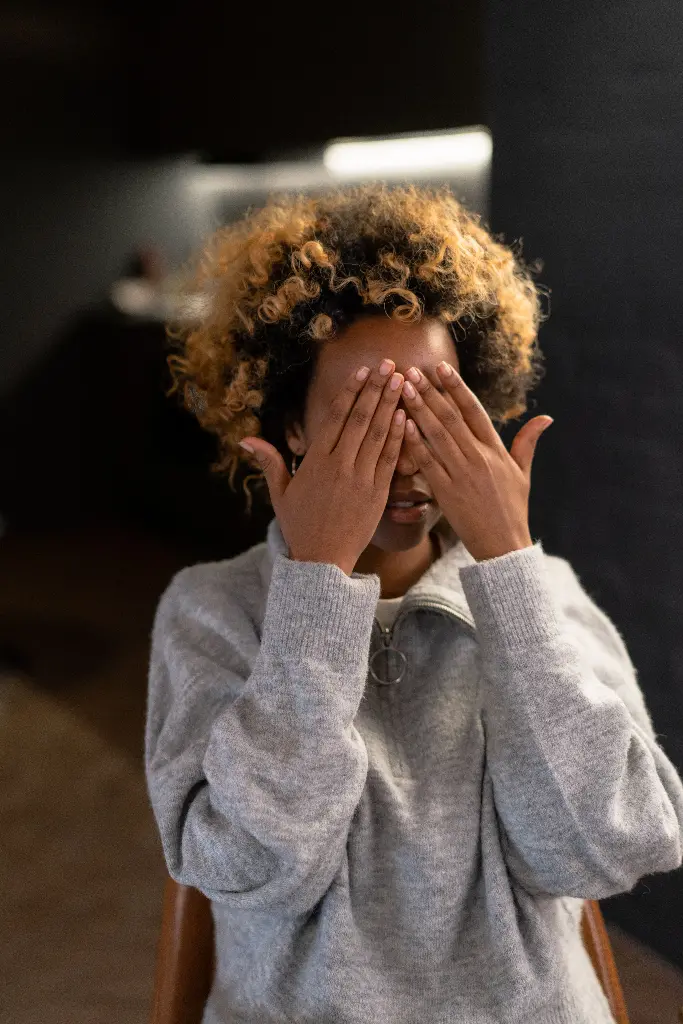 Person covering face with hands, playing hide and seek. Image depicting hidden.