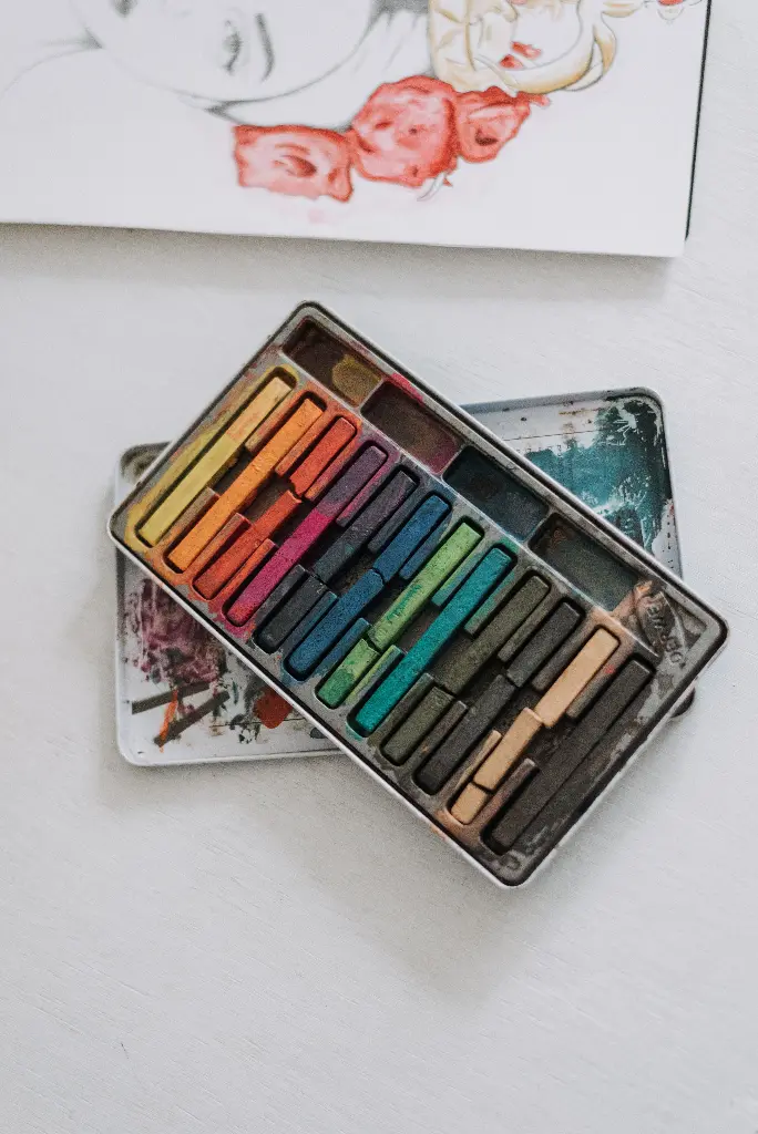 Colorful art kit with pastels and drawing pad. Image depicting kit.