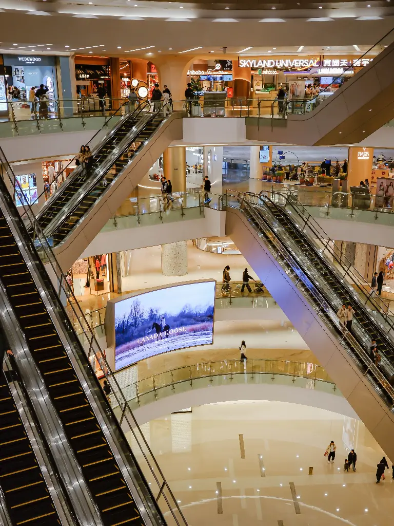 Busy shopping mall with escalators and stores. Image depicting mall.