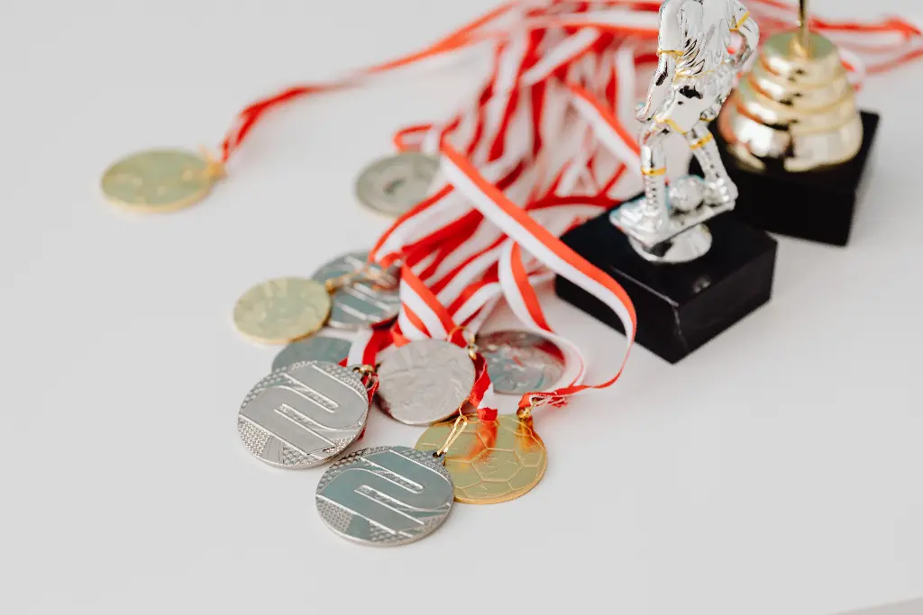 Gold and silver medals with red ribbons on display. Image depicting medals.