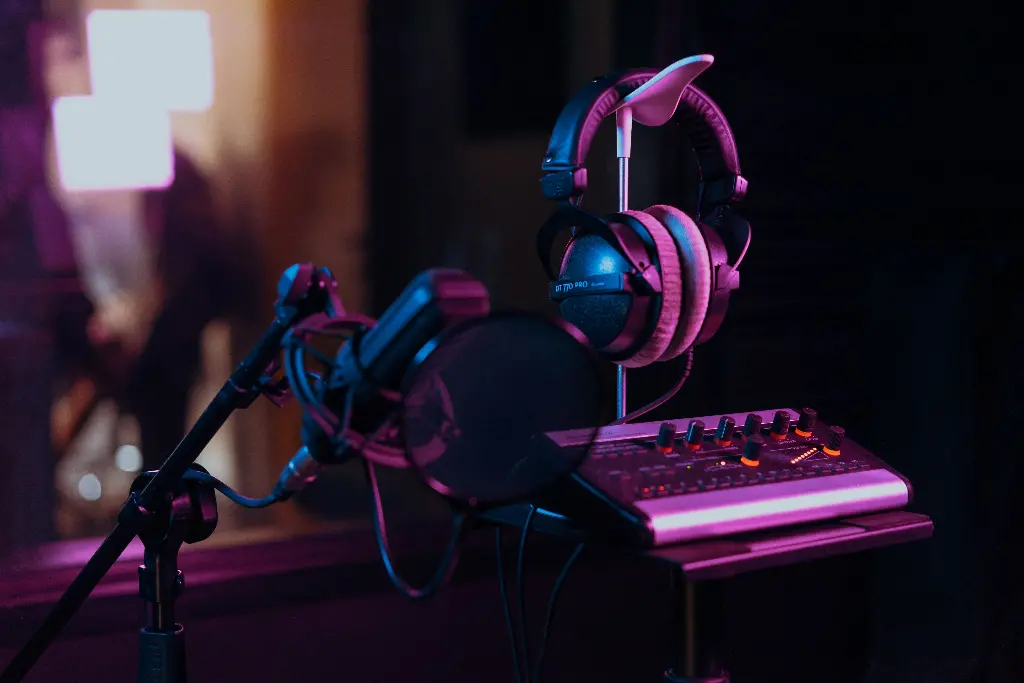 Microphone and headphones in recording studio with colorful lights. Image depicting record.