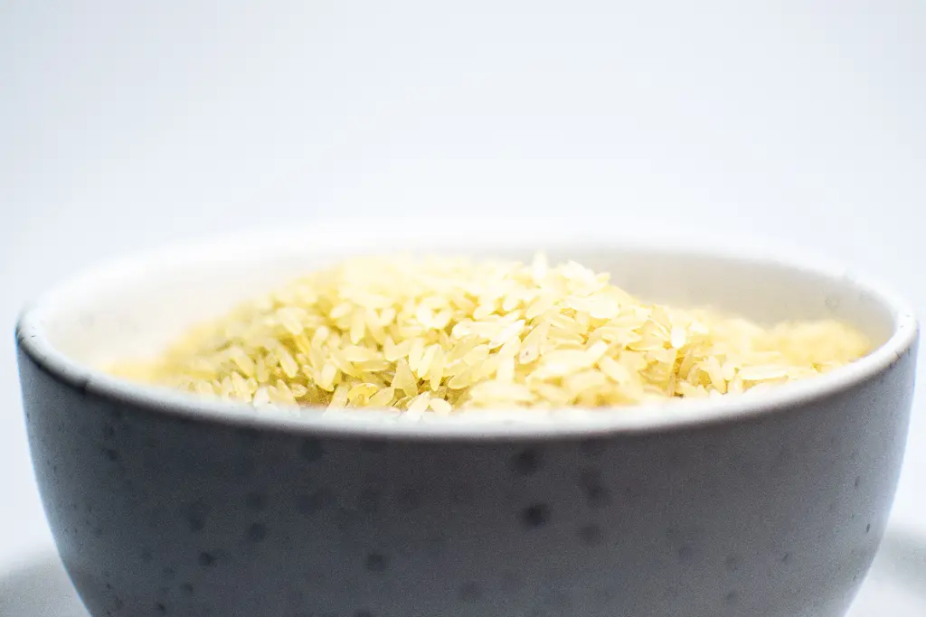 Bowl filled with uncooked white rice grains. Image depicting rice.