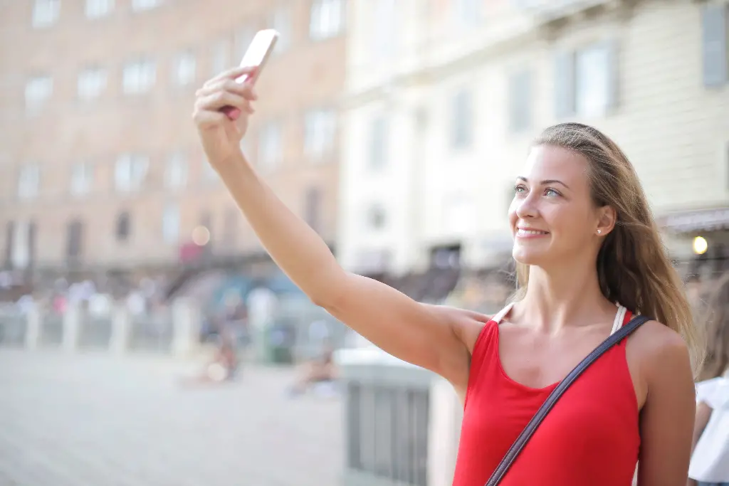 Person taking a selfie outdoors with a smartphone. Image depicting selfie.