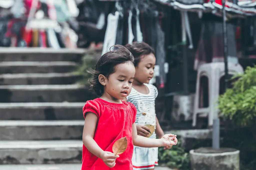 Two smiling children holding leaves outdoors. Image depicting smail.