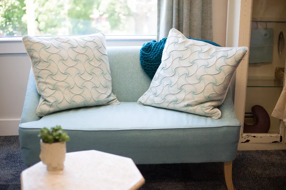 Light blue sofa with patterned cushions in cozy room. Image depicting sofa.